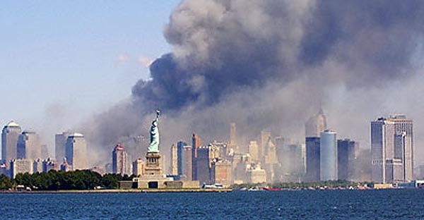 The day after 9/11, the Statue of Liberty stands against a smoke-filled lower Manhattan skyline.