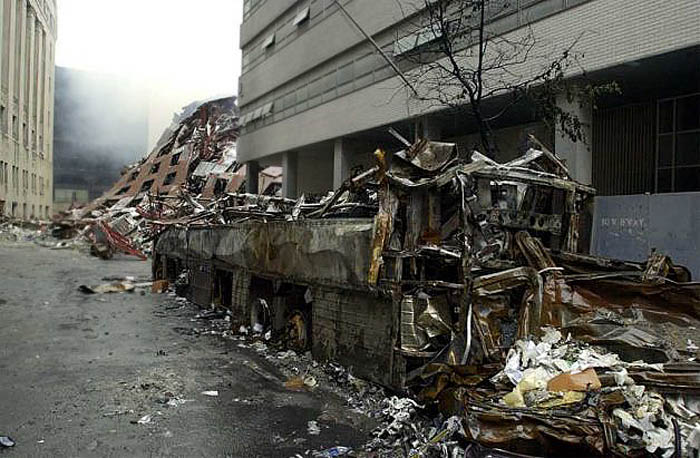 911 WTC area: a charred bus with the collapsed 7 WTC buildng at the end of the street.